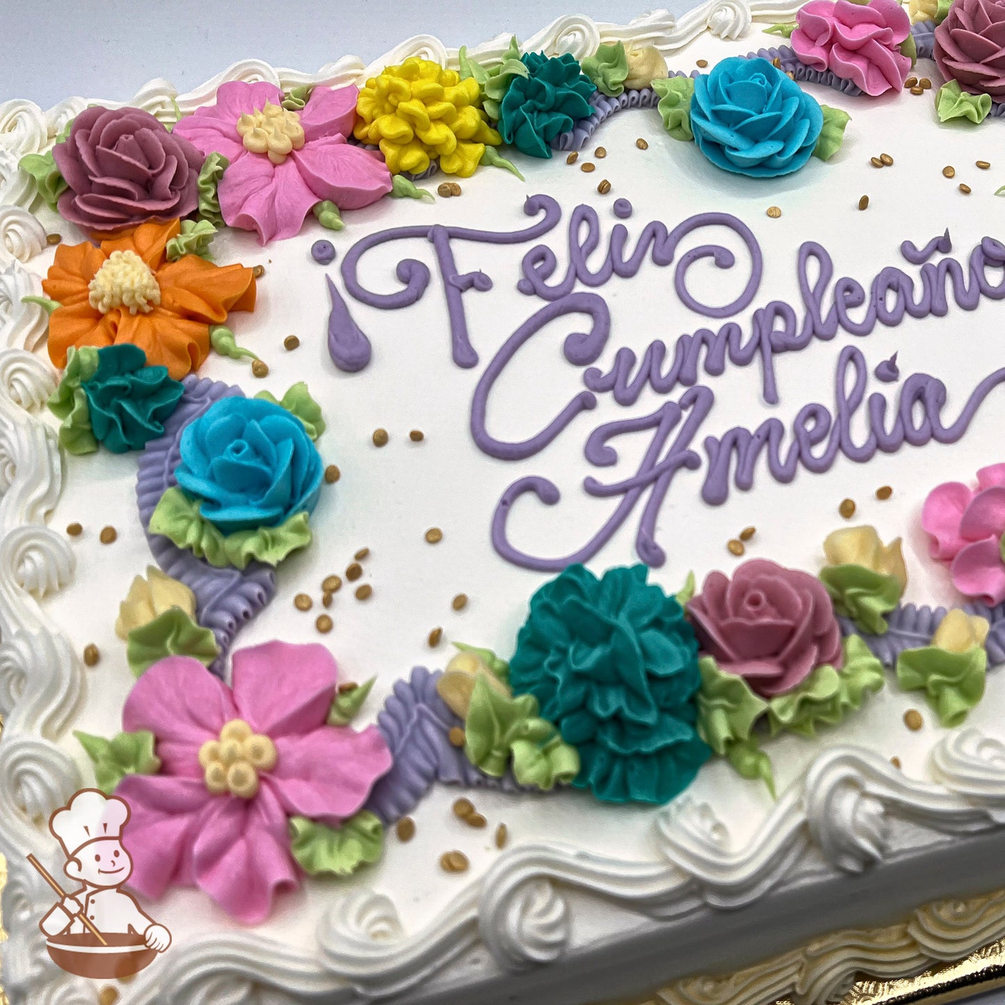 Sheet cake with white buttercream frosting, decorated with colorful buttercream flowers including roses, blossoms, and other florals in pink, orange, yellow, and blue.