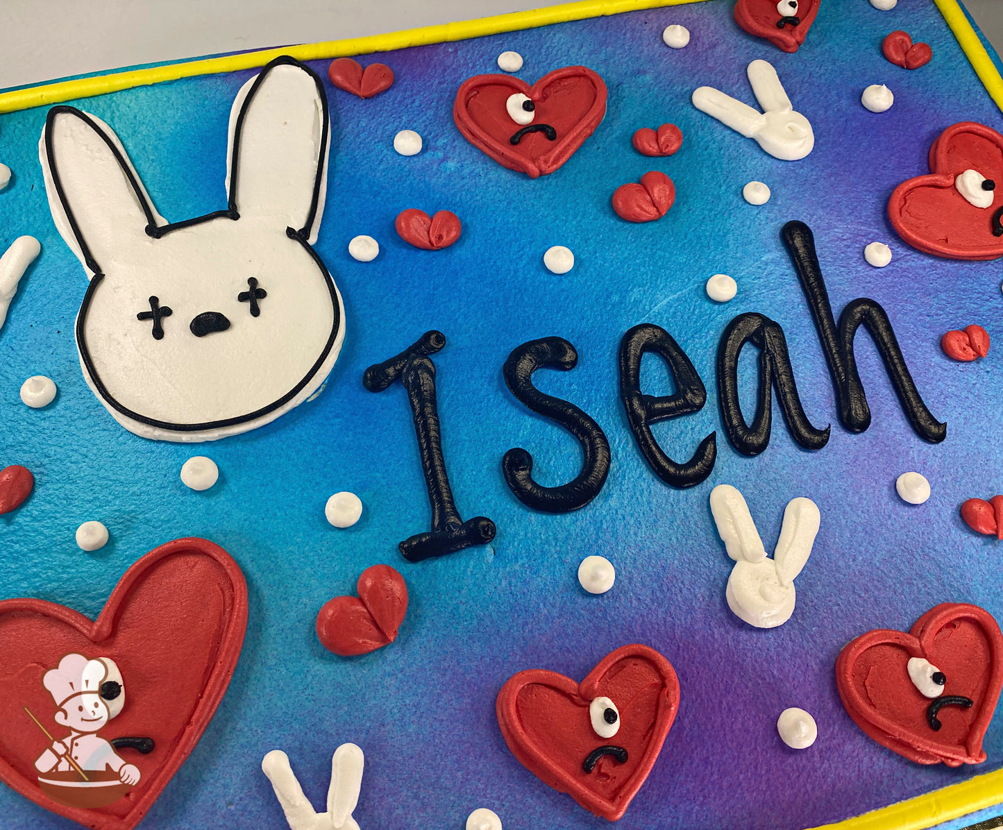 Sheet cake with ombre blue and purple background, featuring a white bunny face, red hearts with eyes, and small white dots.