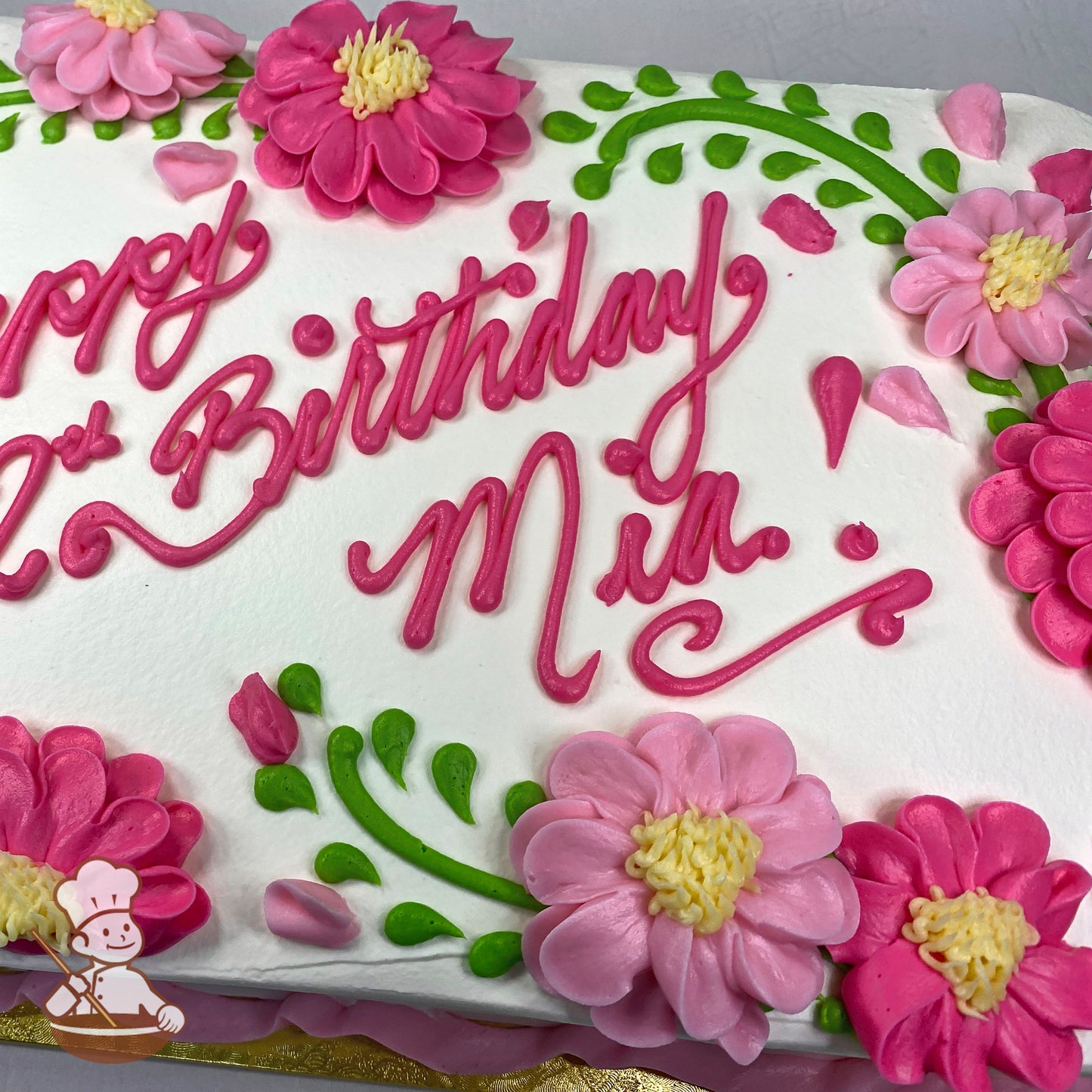 Sheet cake with pink buttercream flowers resembling daisies, green vine accents, and small pink petals on white frosting.