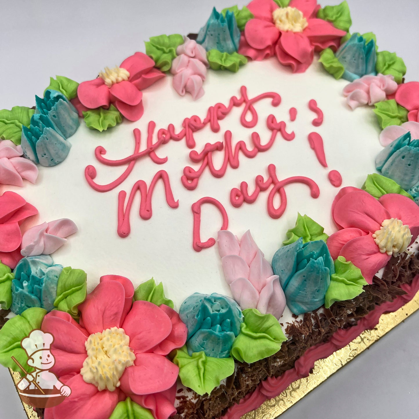 Sheet cake with white buttercream frosting, decorated with blue freesia, pink blossoms, and green leaves.