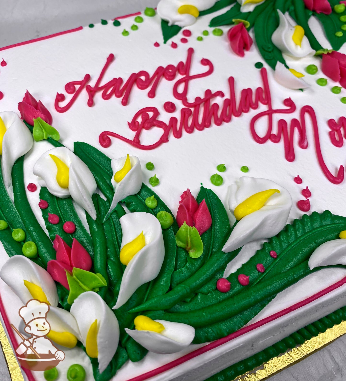 Sheet cake with buttercream decorations featuring white calla lilies with yellow centers, pink buds, green leaves, and small pink and green dots.