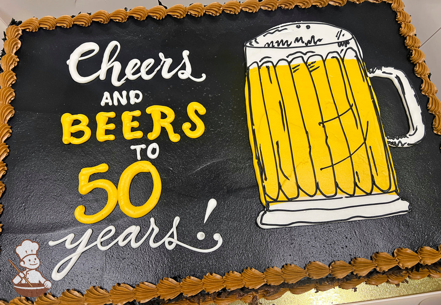 Sheet cake with black background, yellow beer mug decoration on the right, and brown buttercream border.