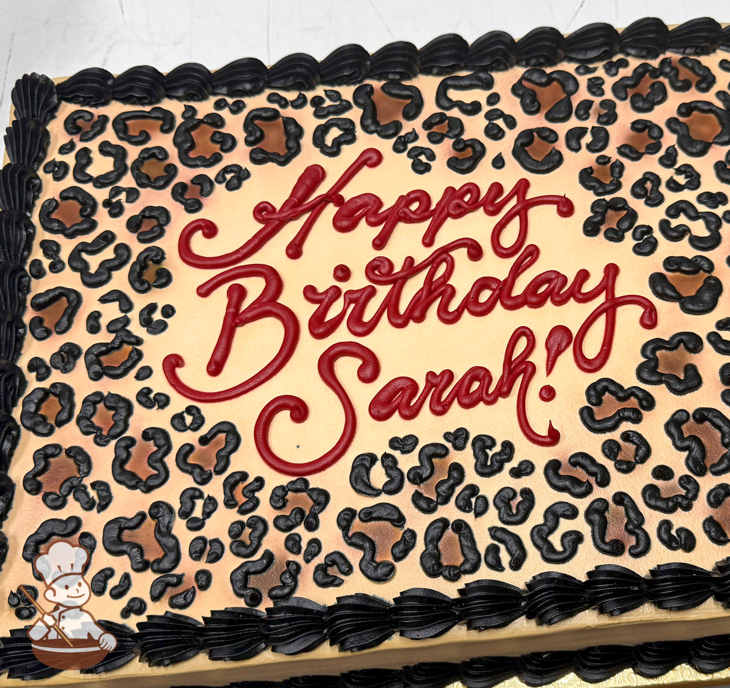 Sheet cake with tan base, black and brown cheetah print pattern, and black piped border.