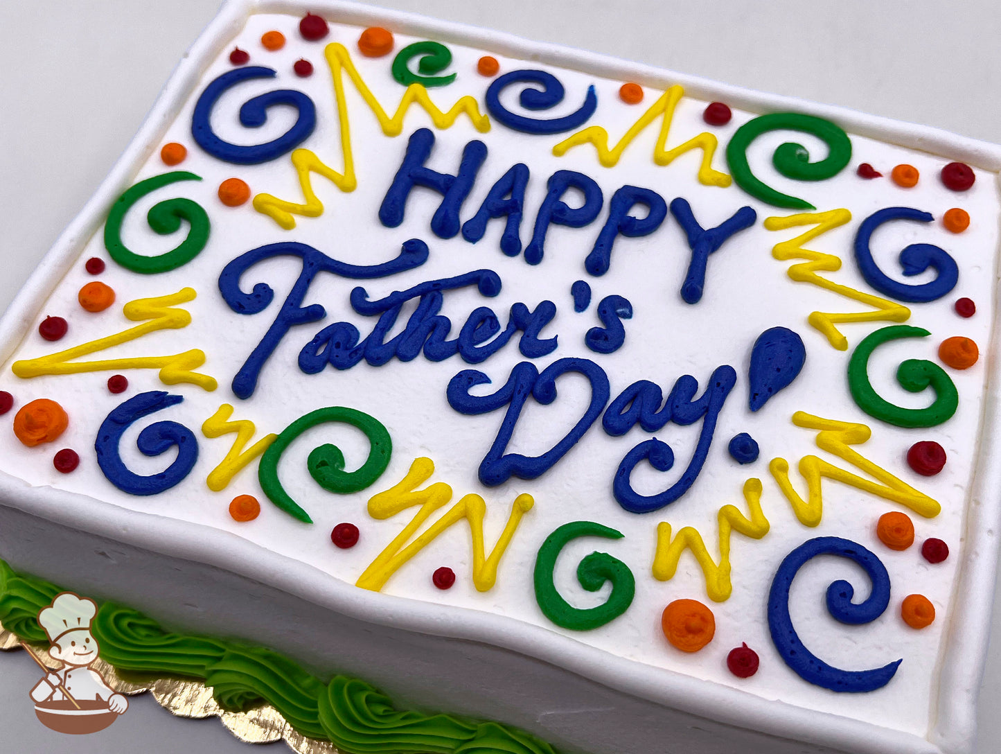 Sheet cake with white frosting, decorated with colorful swirls, dots, and bursts in green, yellow, orange, red, and blue. Green border piping.