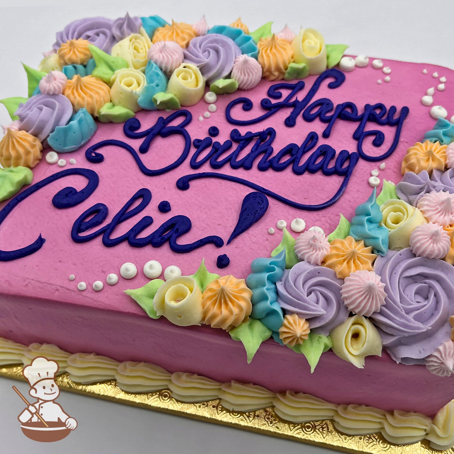 Pink sheet cake with buttercream swirls and rosettes in pastel colors, including purple, yellow, and blue, accented with green leaves.