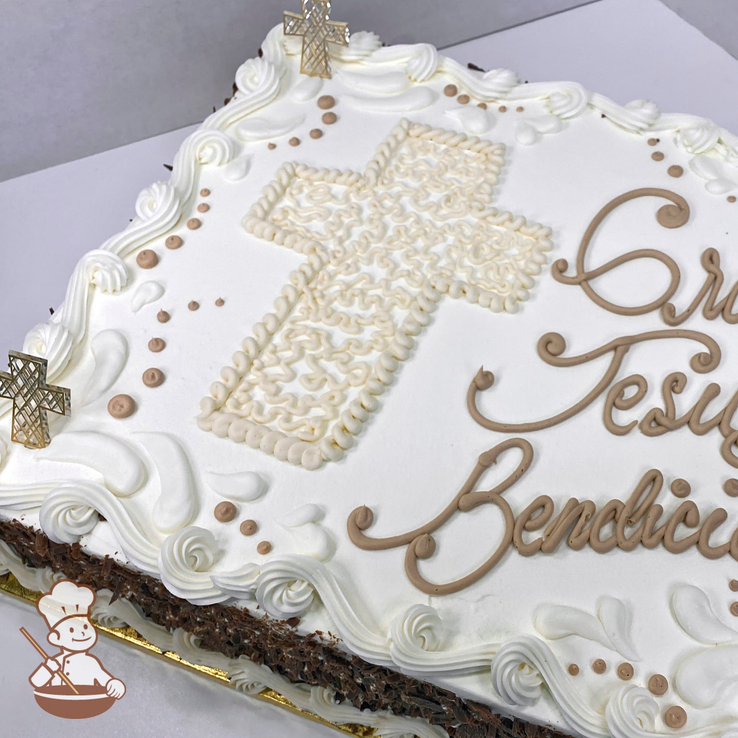 Sheet cake with a buttercream Cornelli lace cross, surrounded by swirls and dots. Two plastic cross rings are placed on the cake.