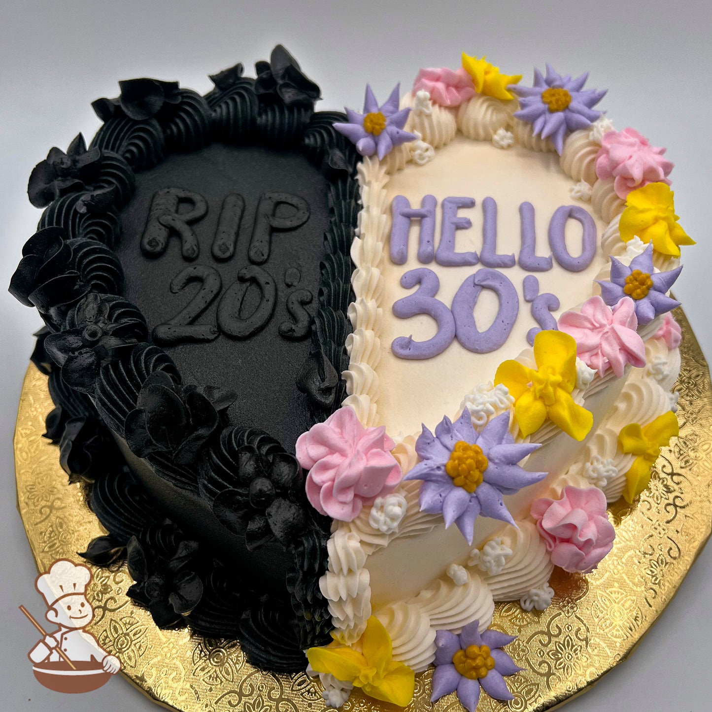 Half-black and half-beige heart cake, decorated with black buttercream flowers on the black side and pastel buttercream flowers—in yellow, purple, and pink—on the beige side.