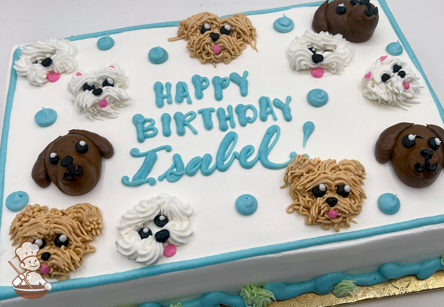 Sheet cake with buttercream dog faces, including brown and white dogs, and blue dots. Blue and green piping decorates the borders.
