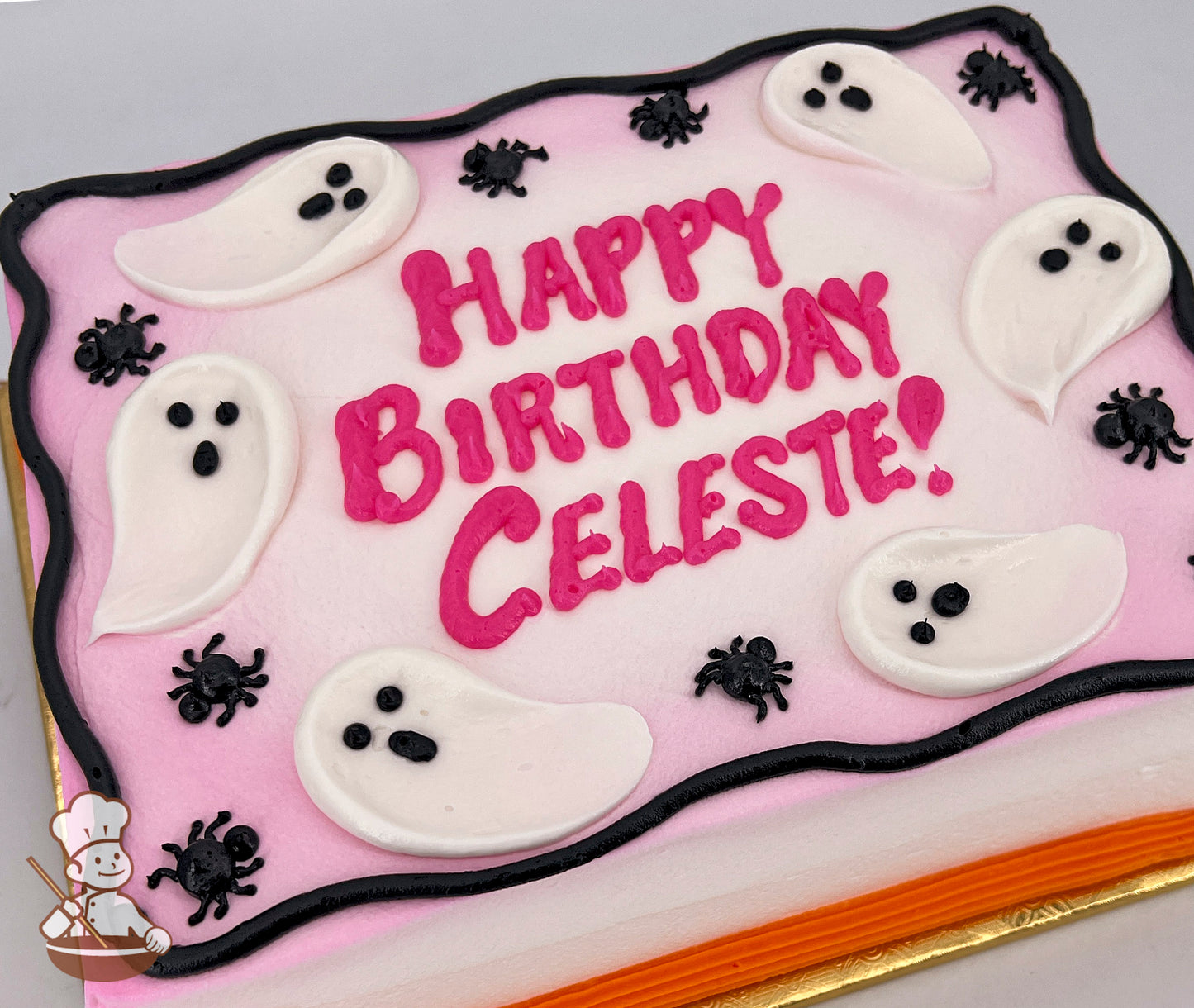 A sheet cake with pink frosting, decorated with white ghost shapes and black spider designs. Black and orange borders accent the cake.