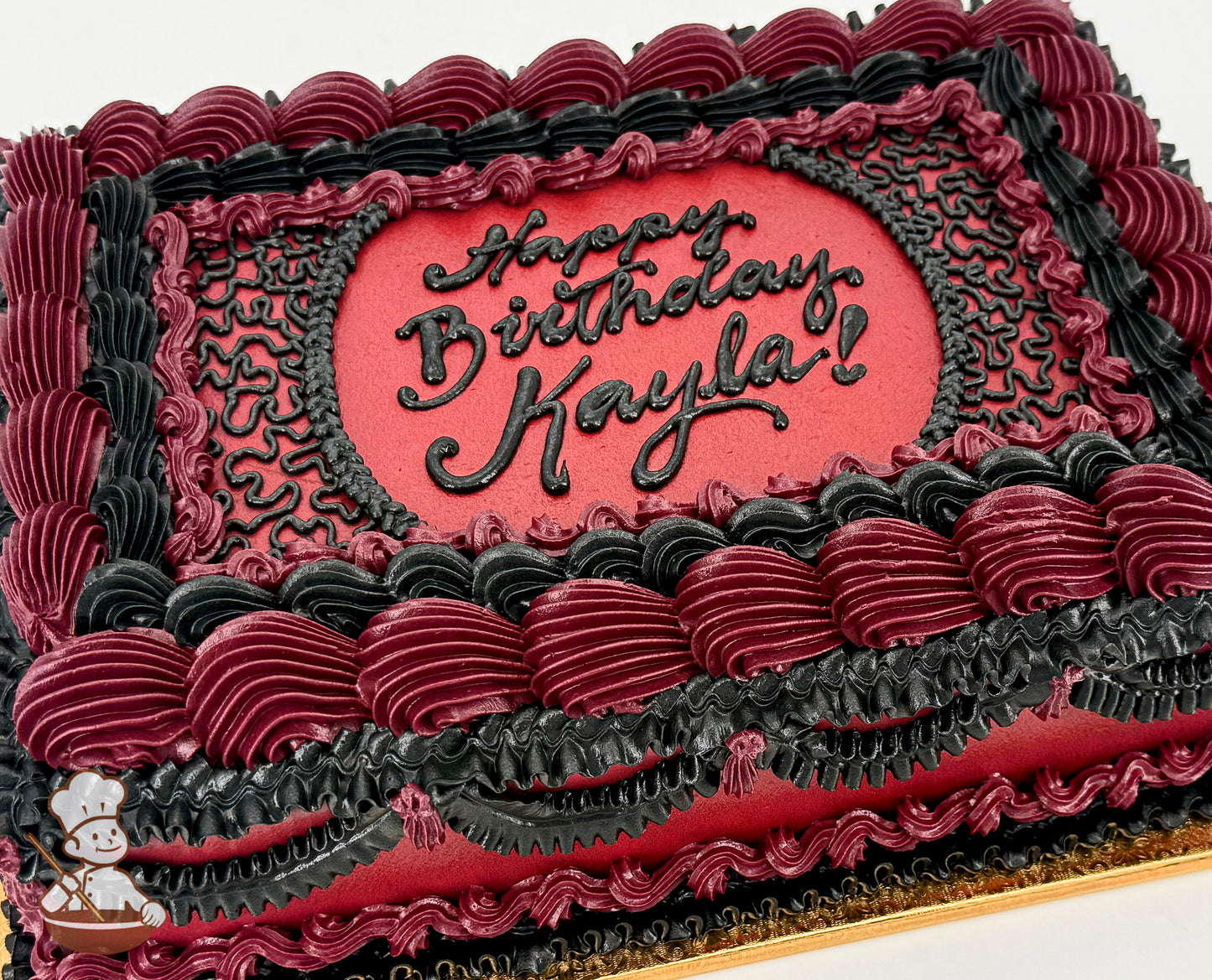 Rectangular sheet cake with deep red and black buttercream piping, featuring ornate vintage-style swirls, ruffles, and lace-like patterns.