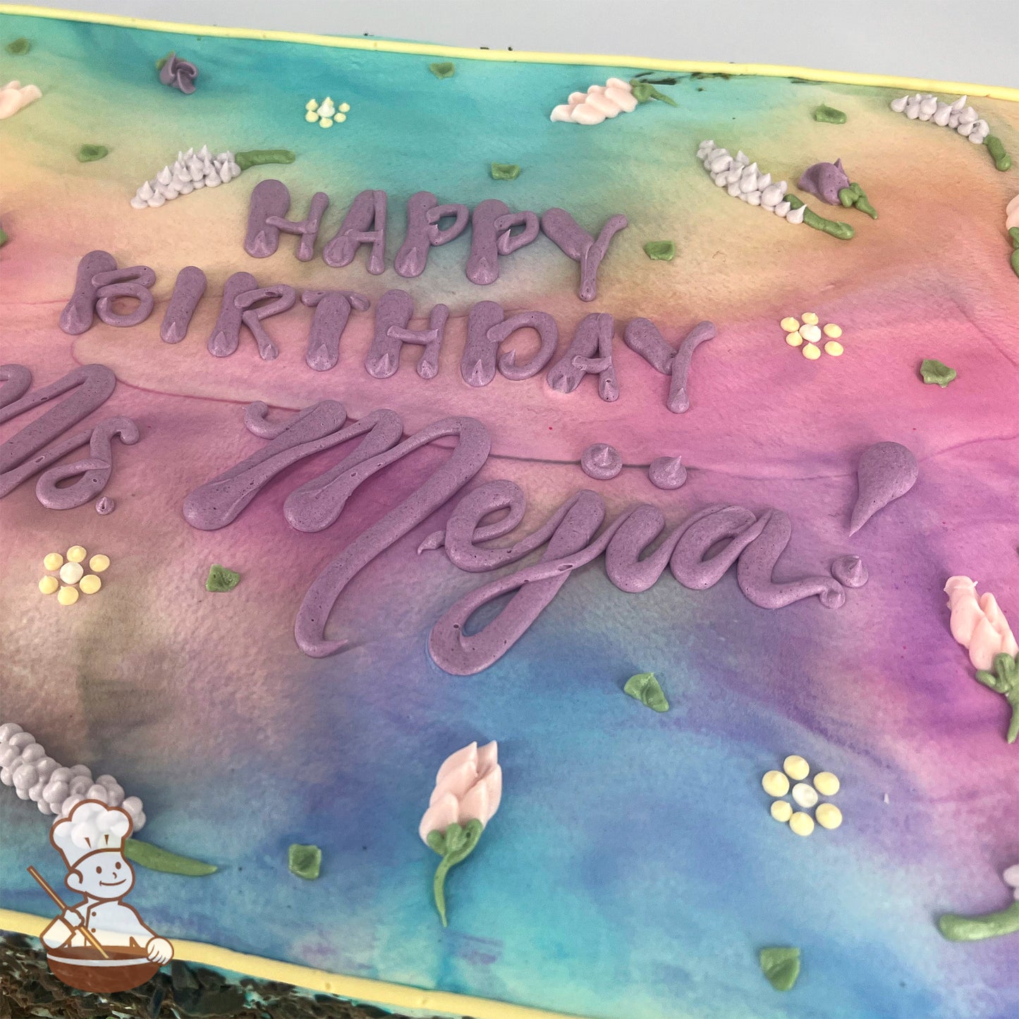 Sheet cake with a pastel gradient background of pink, purple, and blue, decorated with buttercream lavender flowers, small yellow blossoms, and green leaves.