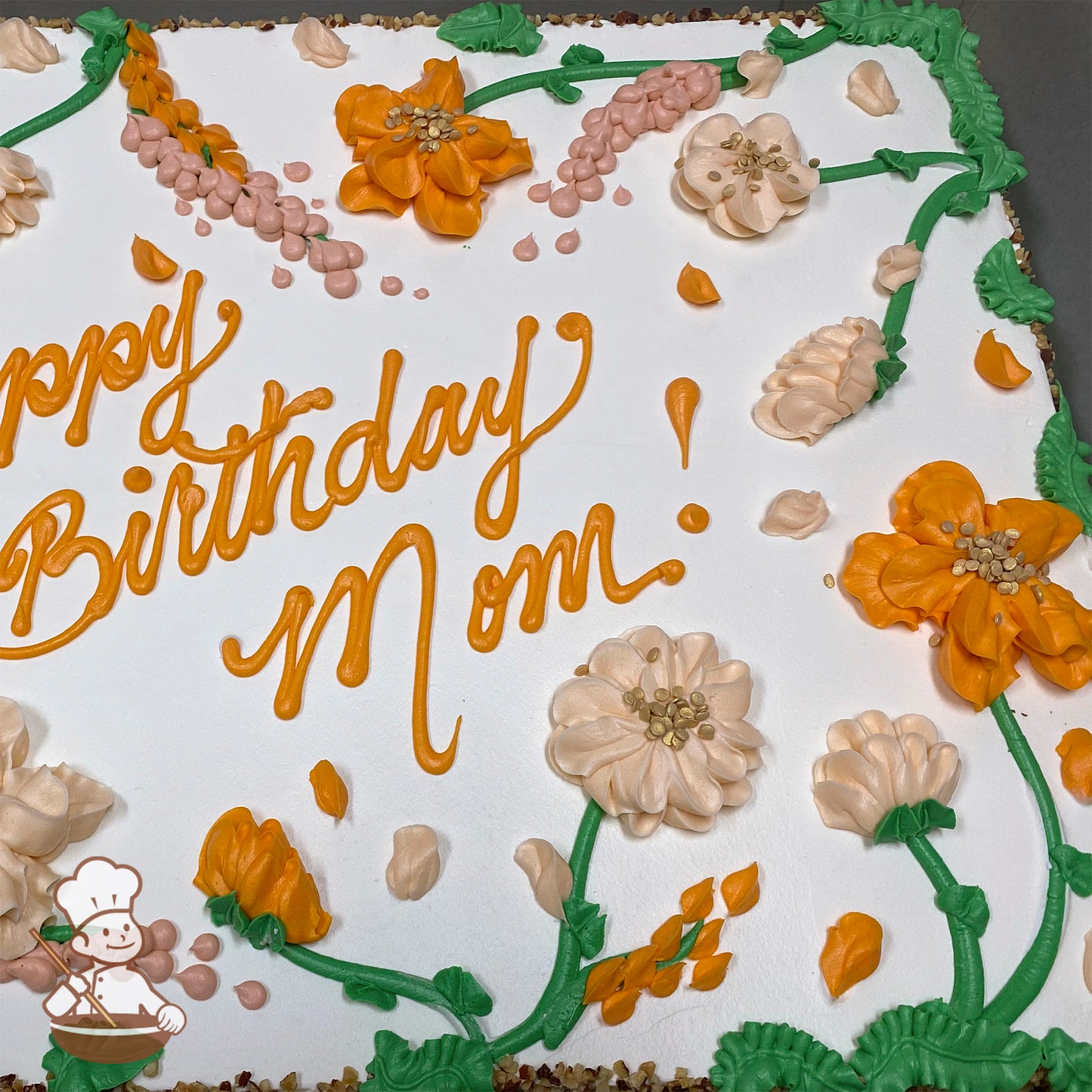 Sheet cake with white frosting, decorated with orange and peach buttercream flowers, green stems, and pink lupine-like blossoms.