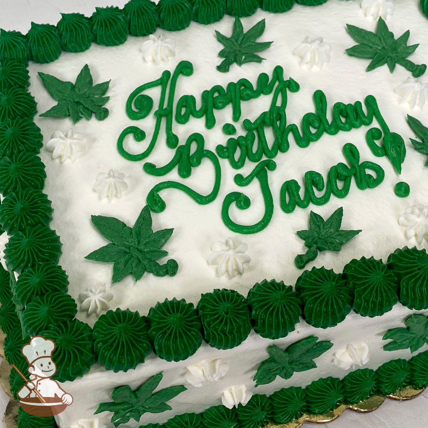 A rectangular sheet cake with white frosting, green marijuana leaf decorations, white star-shaped accents, and a green piped border.