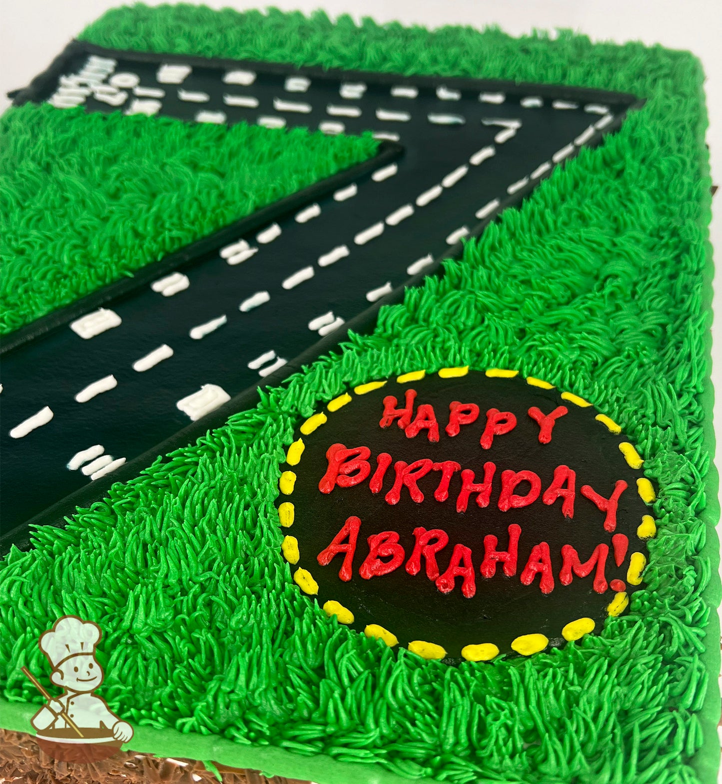 Sheet cake with buttercream grass and a racetrack design. Circular area with yellow border on grass.