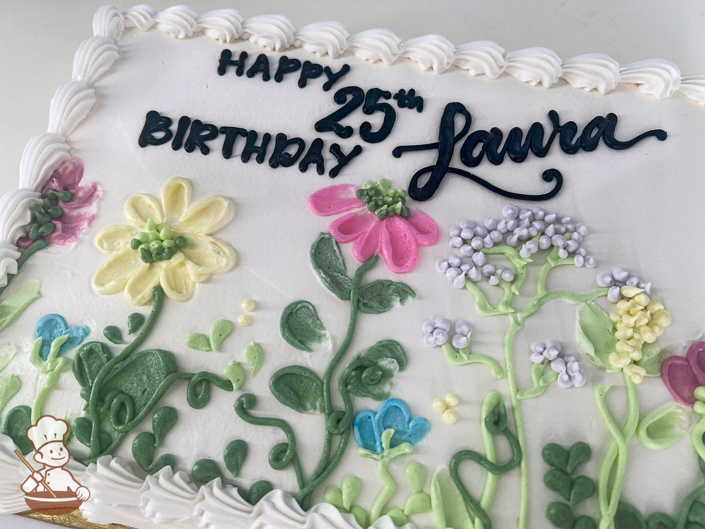 Sheet cake with white frosting, decorated with colorful buttercream flowers including yellow daisies, pink coneflowers, bluebells, lavender sprigs, and green leaves.