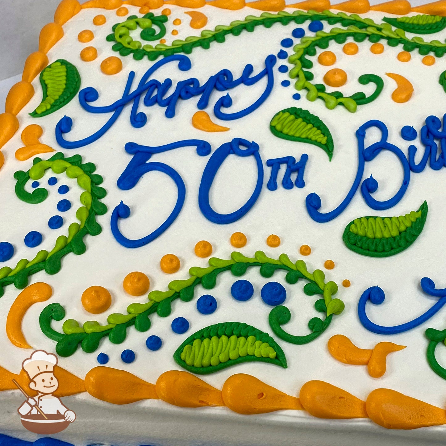 Sheet cake with white frosting, decorated with green and orange swirls, green leaves, blue and orange dots, and an orange border.