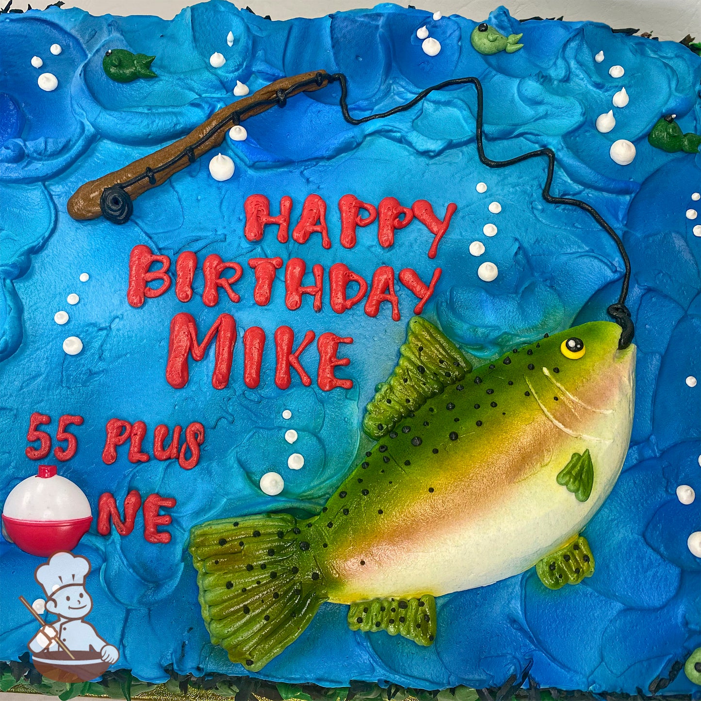 Blue sheet cake with buttercream waves, fishing rod, float, bubbles, and a large fish decoration.