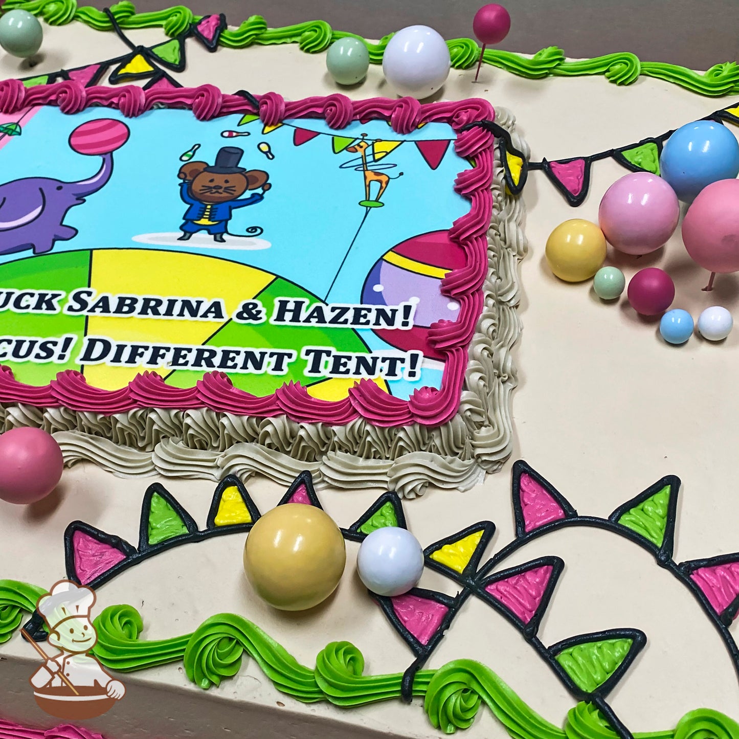Sheet cake with colorful buttercream borders, party banner designs, and bubble toppers in pastel colors. Decorations include green swirls and triangular flags.