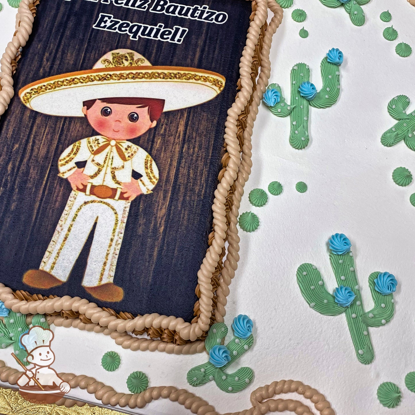 Sheet cake with buttercream cacti, blue buttercream flowers, green dots, and a rope trim border in tan and brown.