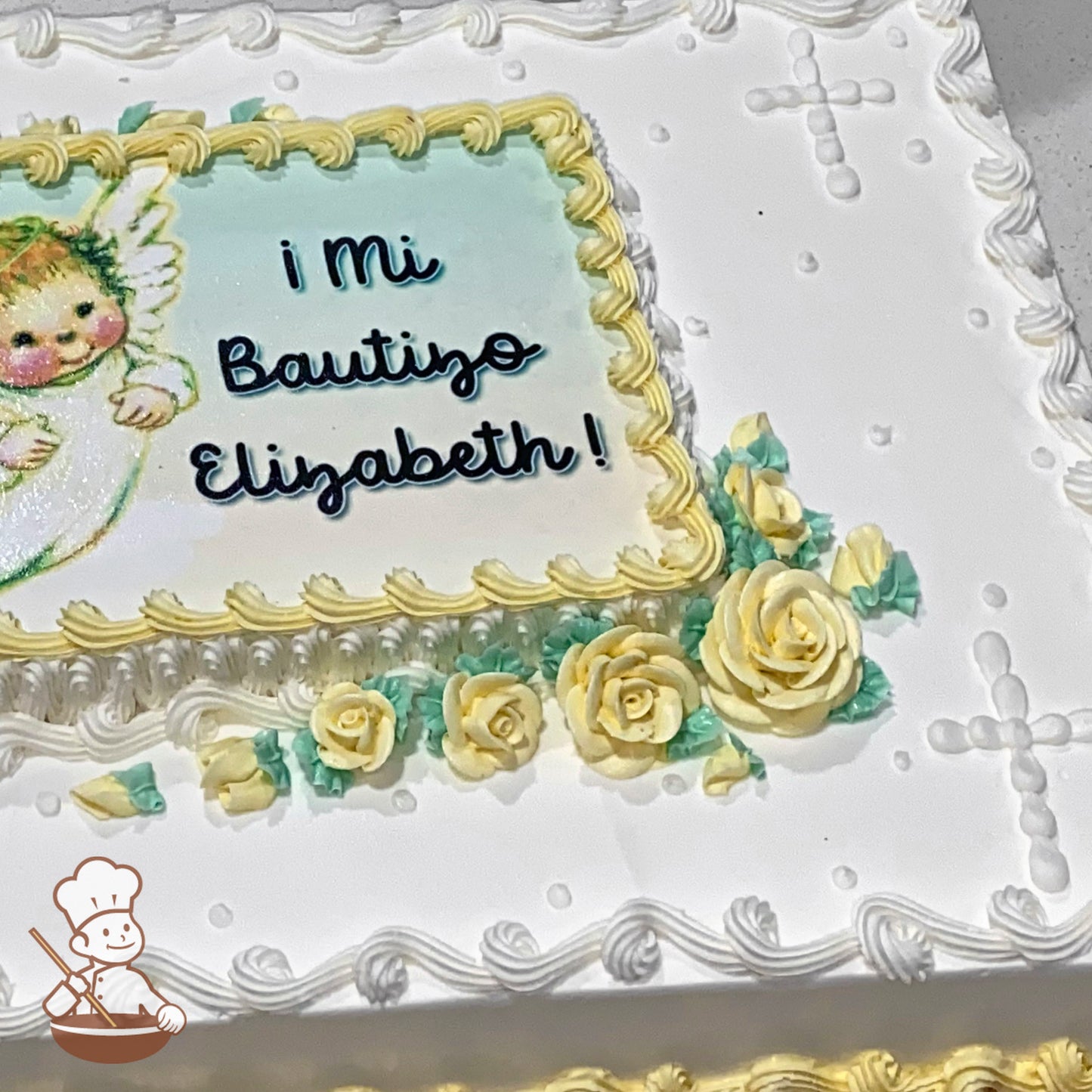 Sheet cake with white frosting, yellow with green buttercream roses, piped borders, and a beaded cross design in the corners.