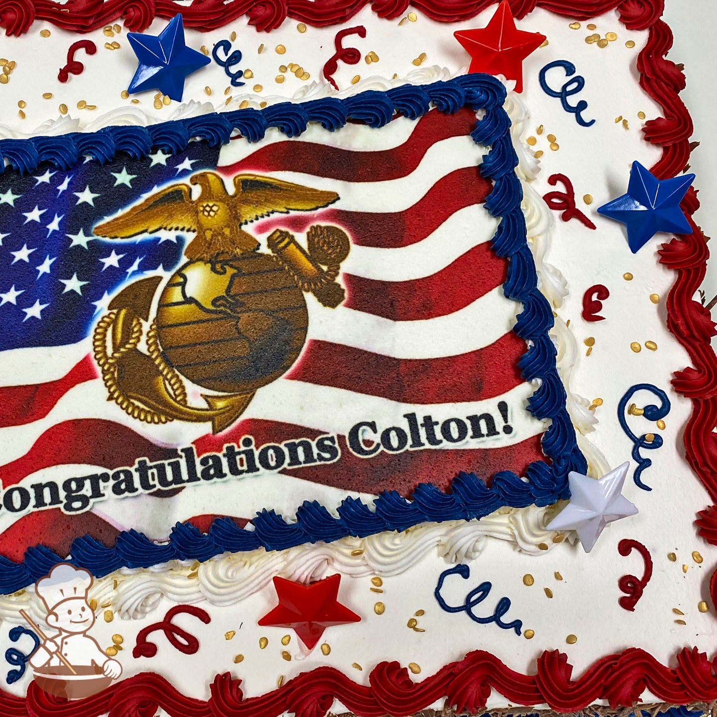 Sheet cake with red, white, and blue buttercream borders, gold confetti sprinkles, plastic red and blue star decorations, and piped streamers.