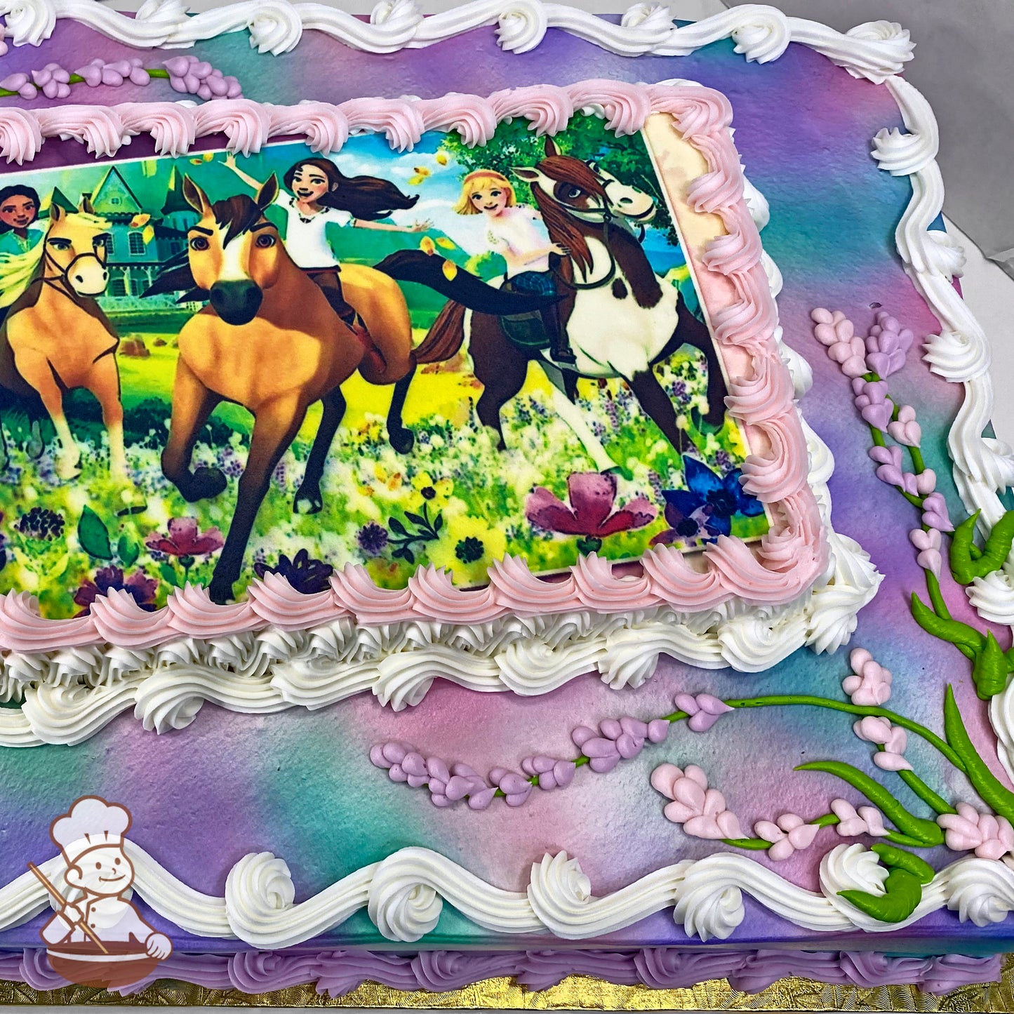 Sheet cake with ombre purple and blue base, white and pink piped borders, and hand-piped lavender sprigs on the corners.