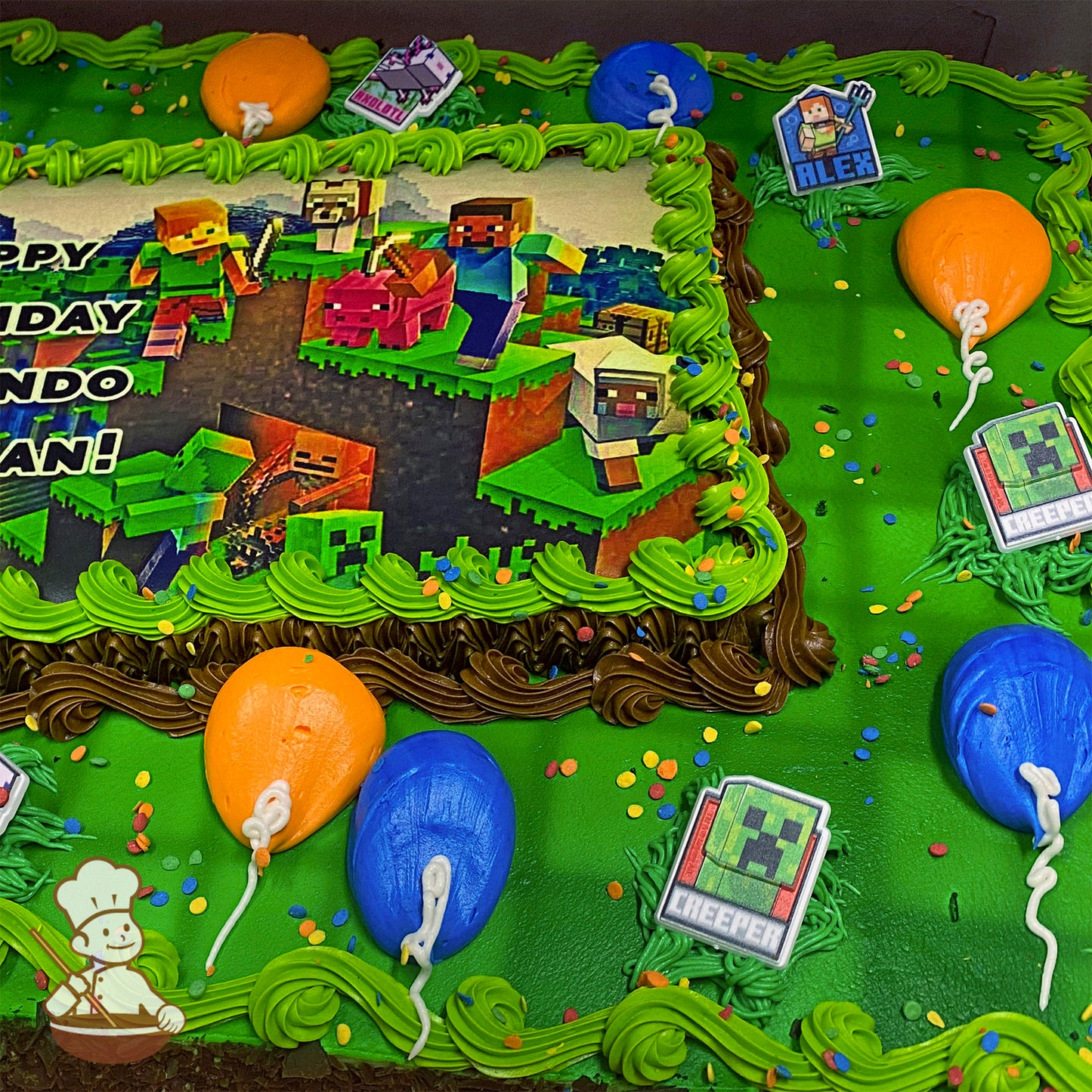 Sheet cake with green buttercream borders, colorful sprinkles, orange and blue balloon decorations, and plastic Minecraft-themed toppers.
