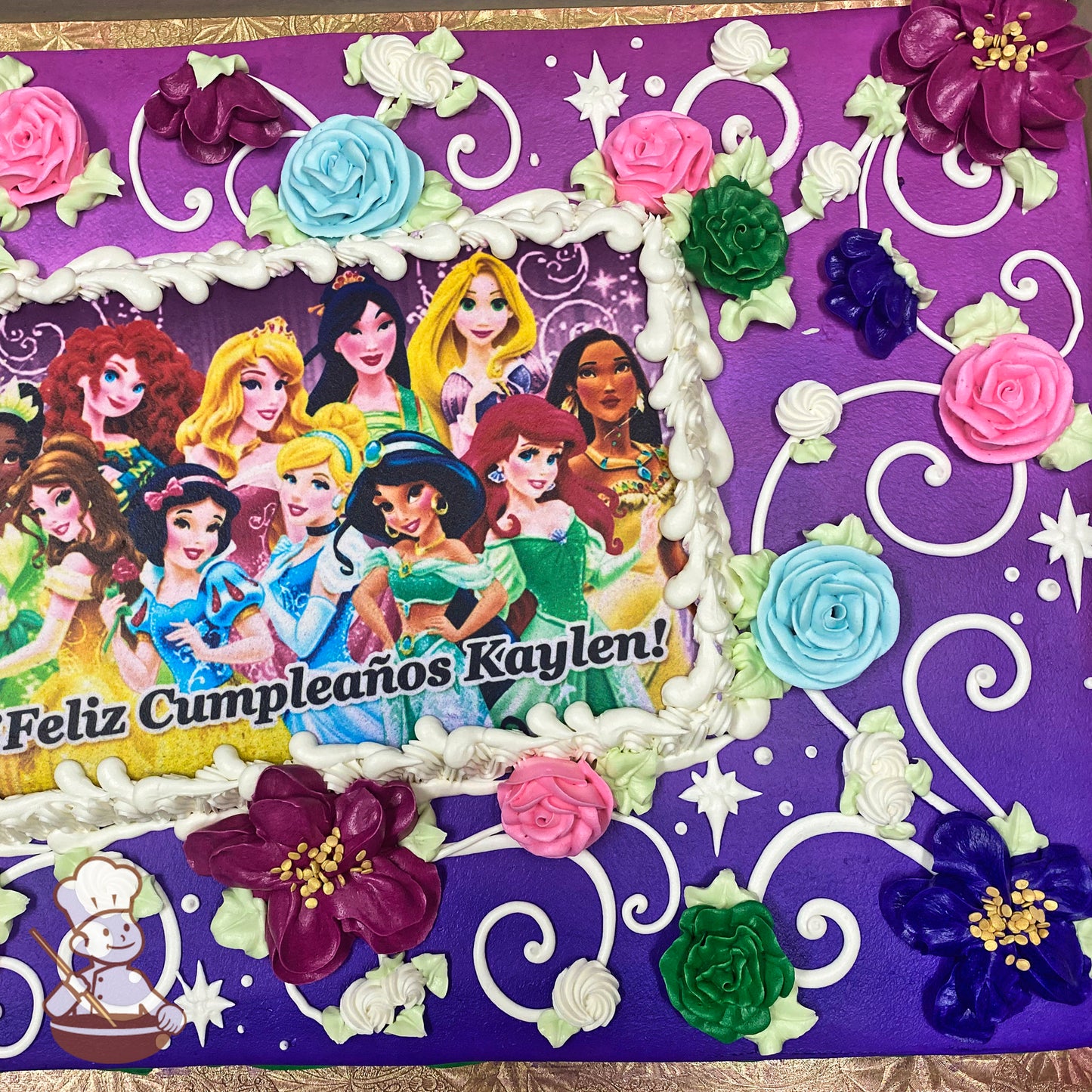 Purple sheet cake with colorful buttercream roses in pink, blue, and green, white swirls, stars, and floral accents surrounding a central printed image.