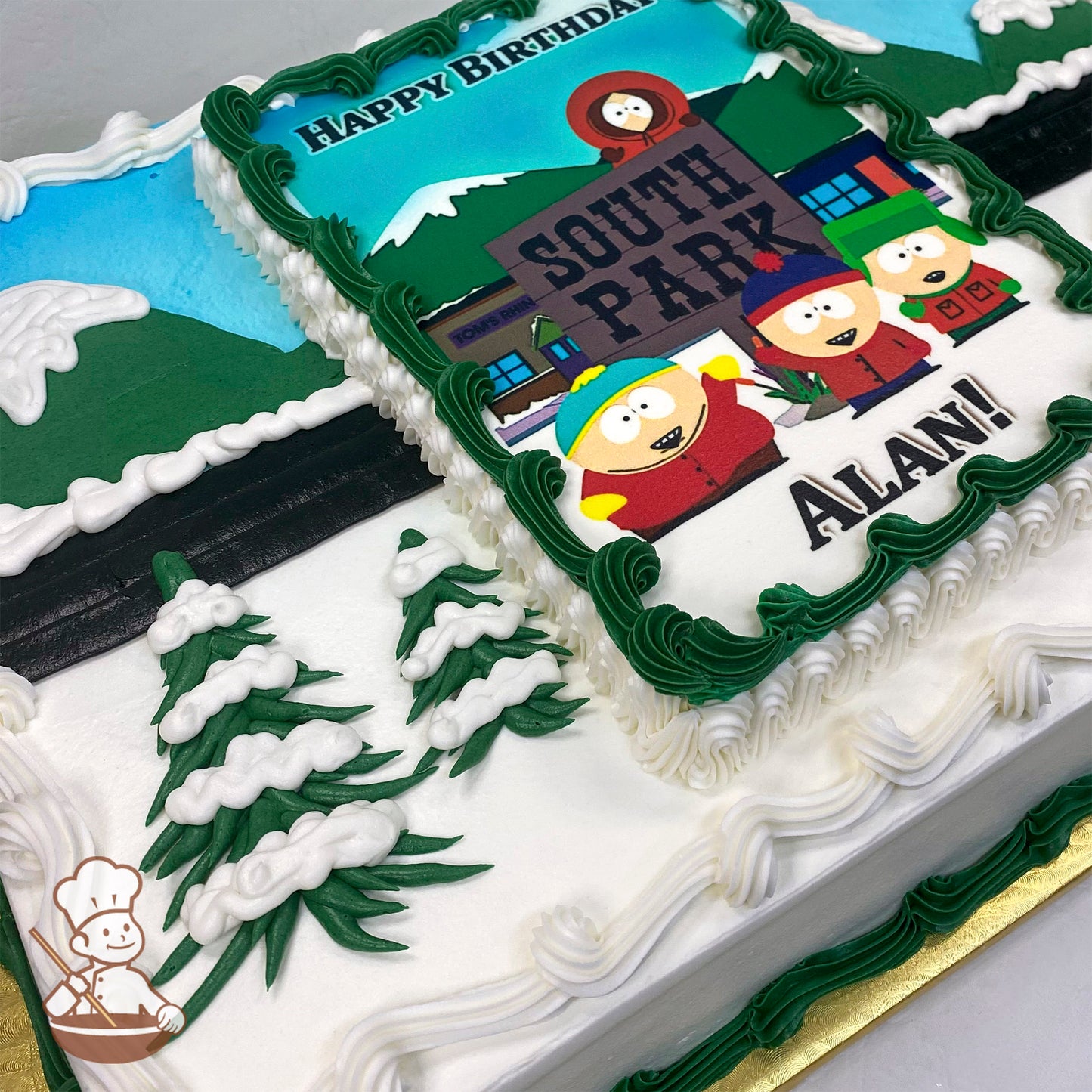 Sheet cake with buttercream decorations, featuring snow-capped green trees, white icing borders, and a printed photo layer framed with green icing.