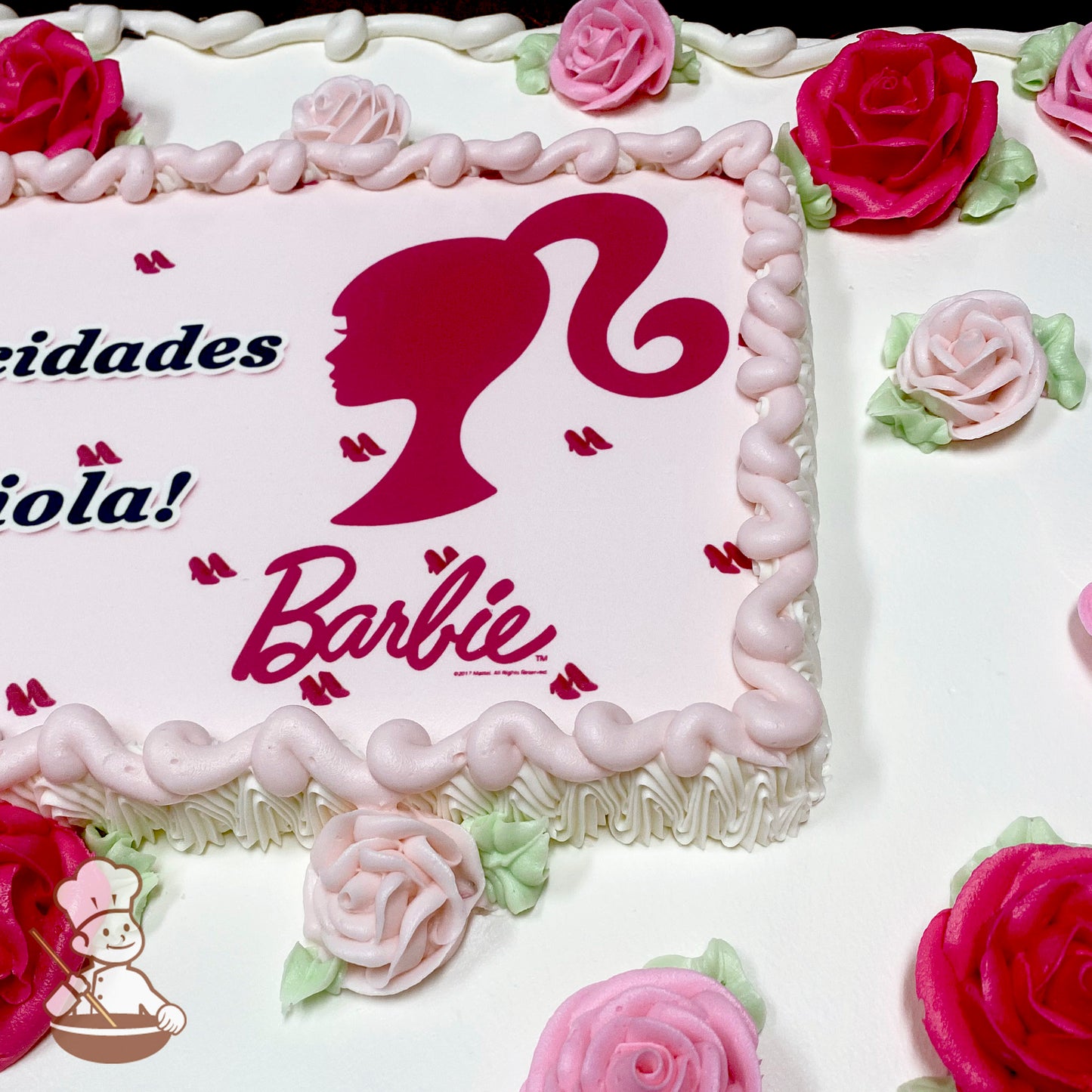 Sheet cake with pink buttercream borders, decorated with pink buttercream roses, green leaves, and a printed photo layer featuring a Barbie theme.