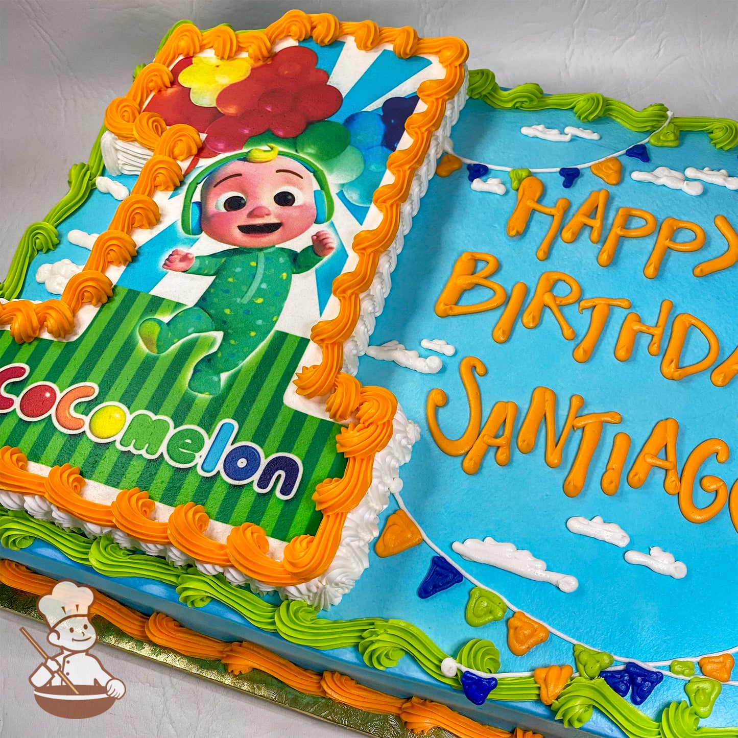 Sheet cake with buttercream decorations, featuring a Cocomelon-themed number "1" cutout with colorful balloons, orange and green borders, and a blue sky design with clouds and bunting.