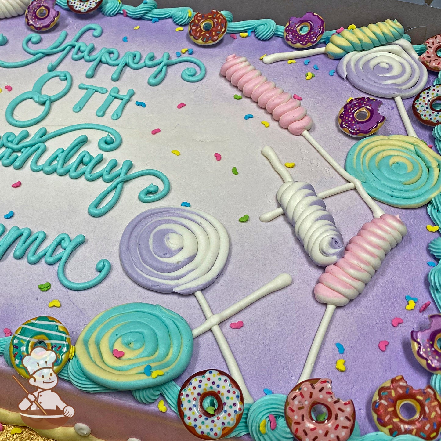 Sheet cake with purple and white gradient background, decorated with pastel buttercream lollipops, plastic donut rings, and colorful sprinkles.
