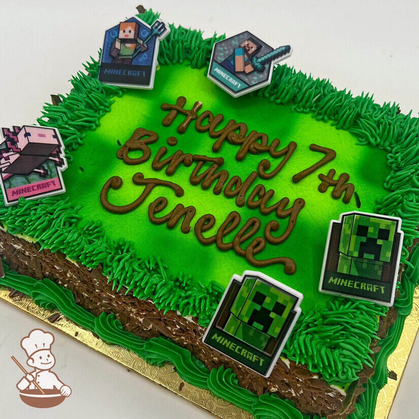 Rectangular sheet cake with green buttercream grass borders, a bright green top, and Minecraft-themed plastic character toppers, including a Creeper.