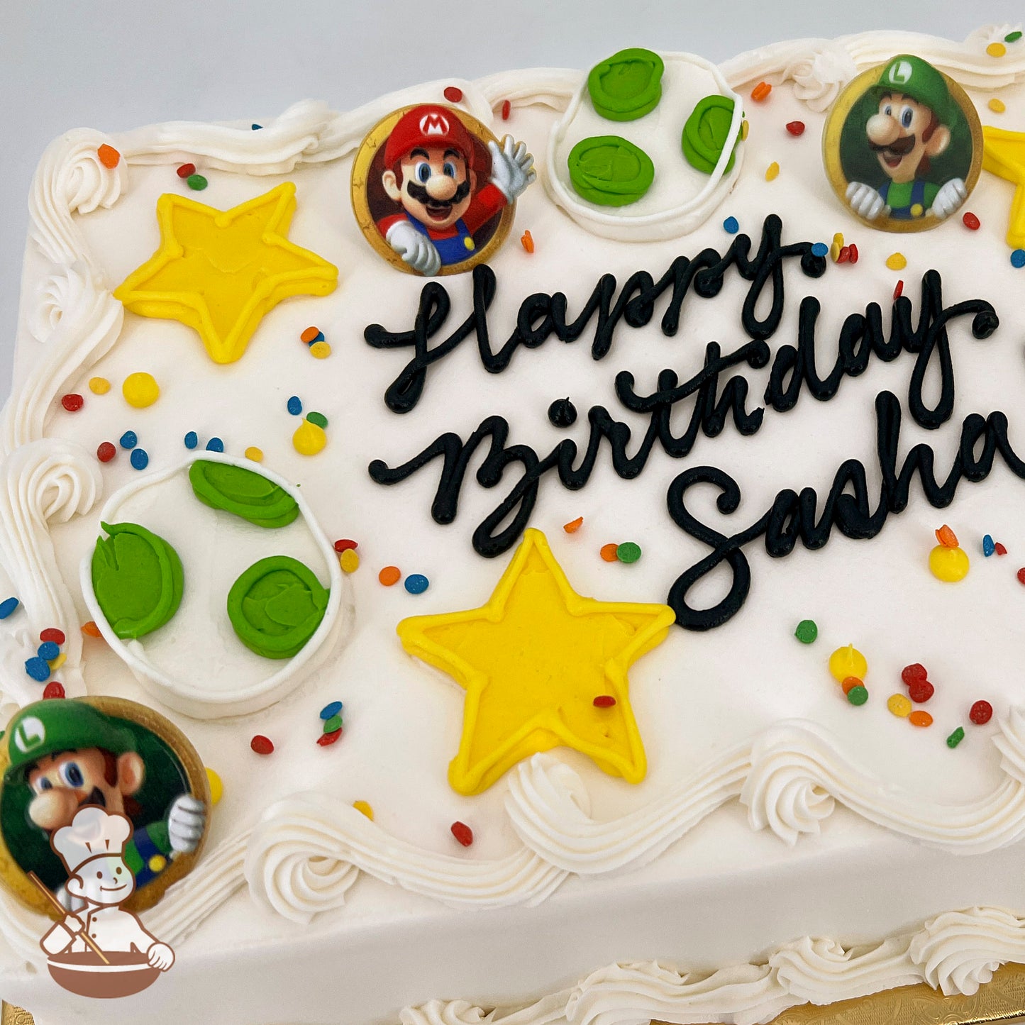 Sheet cake with white frosting, decorated with yellow Super Mario stars, Yoshi egg designs, colorful sprinkles, and plastic rings featuring Mario and Luigi.