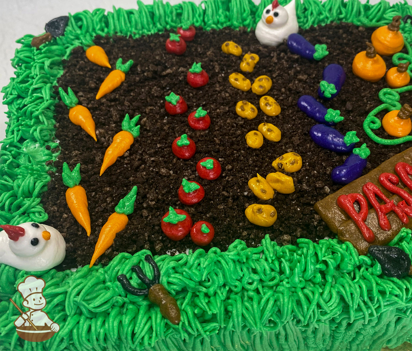 Sheet cake decorated as a garden with buttercream grass, dirt made of cake crumbs, rows of vegetables like carrots, tomatoes, and pumpkins, and small chicken figures.