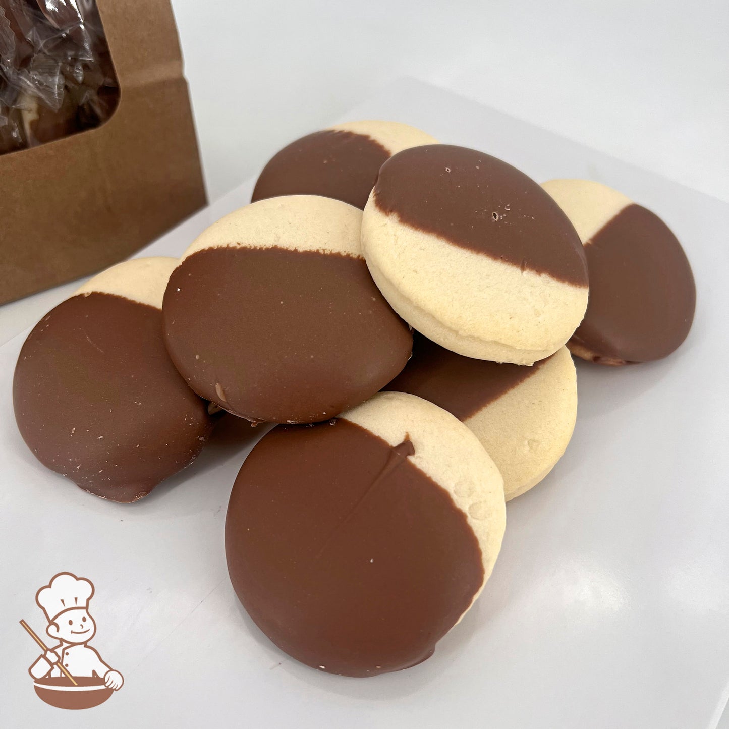 Ten butter shortbread cookies, each half-dipped in Belgian chocolate, are arranged in front of a kraft window bag.