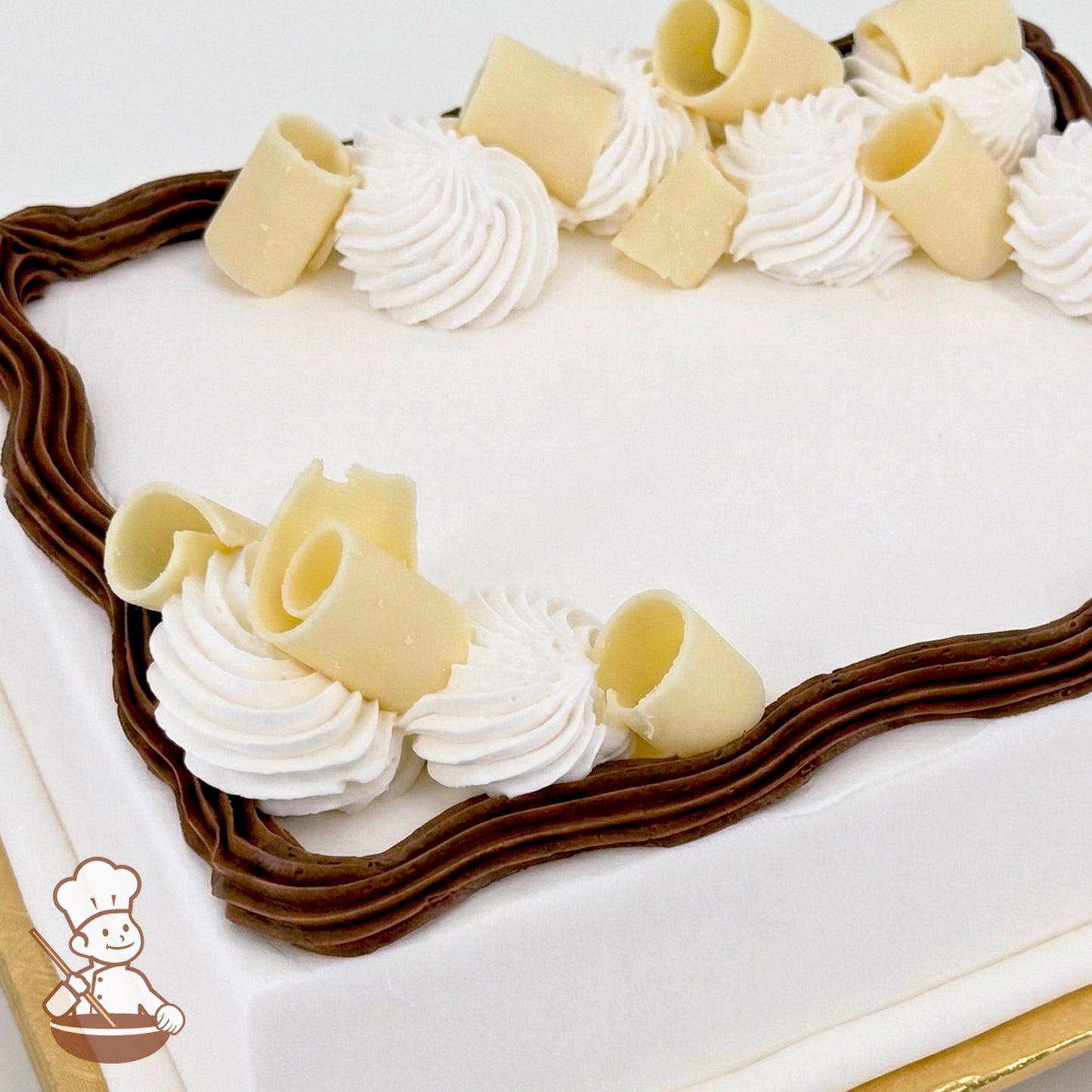 Sheet cake with white frosting, decorated with brown buttercream trim and topped with white chocolate curls and piped white buttercream swirls.