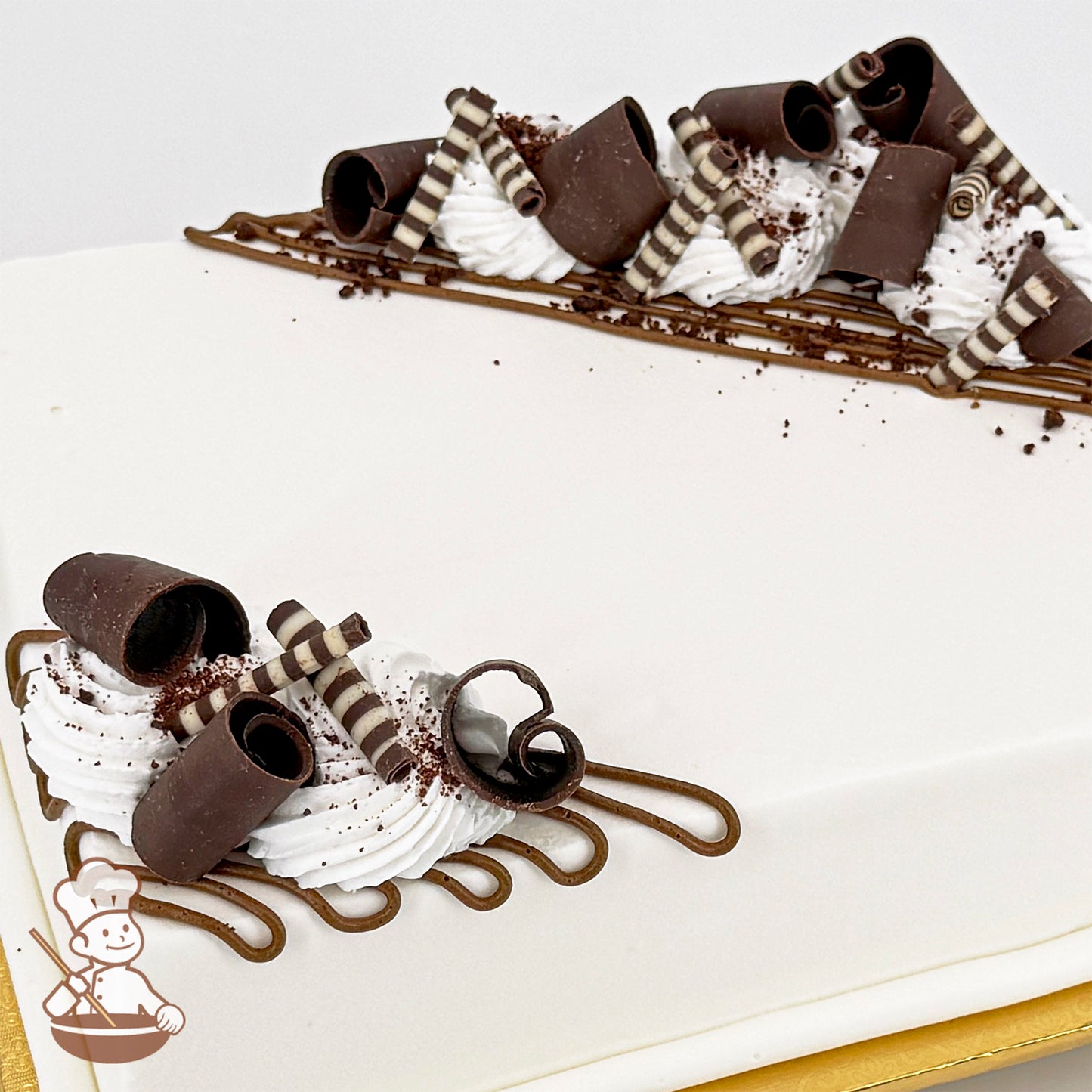 White sheet cake decorated with chocolate curls, striped chocolate sticks, brown buttercream lines, and white buttercream swirls.