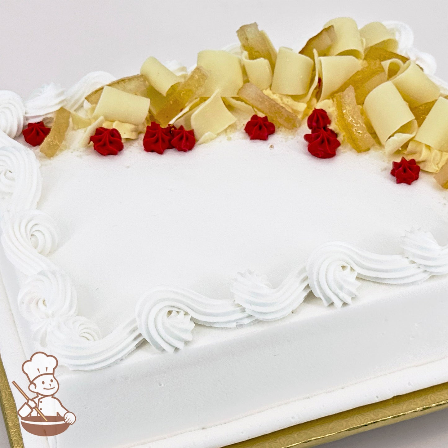 White sheet cake with red buttercream dots, swirled trim, white chocolate curls, and candied lemon peels on top.