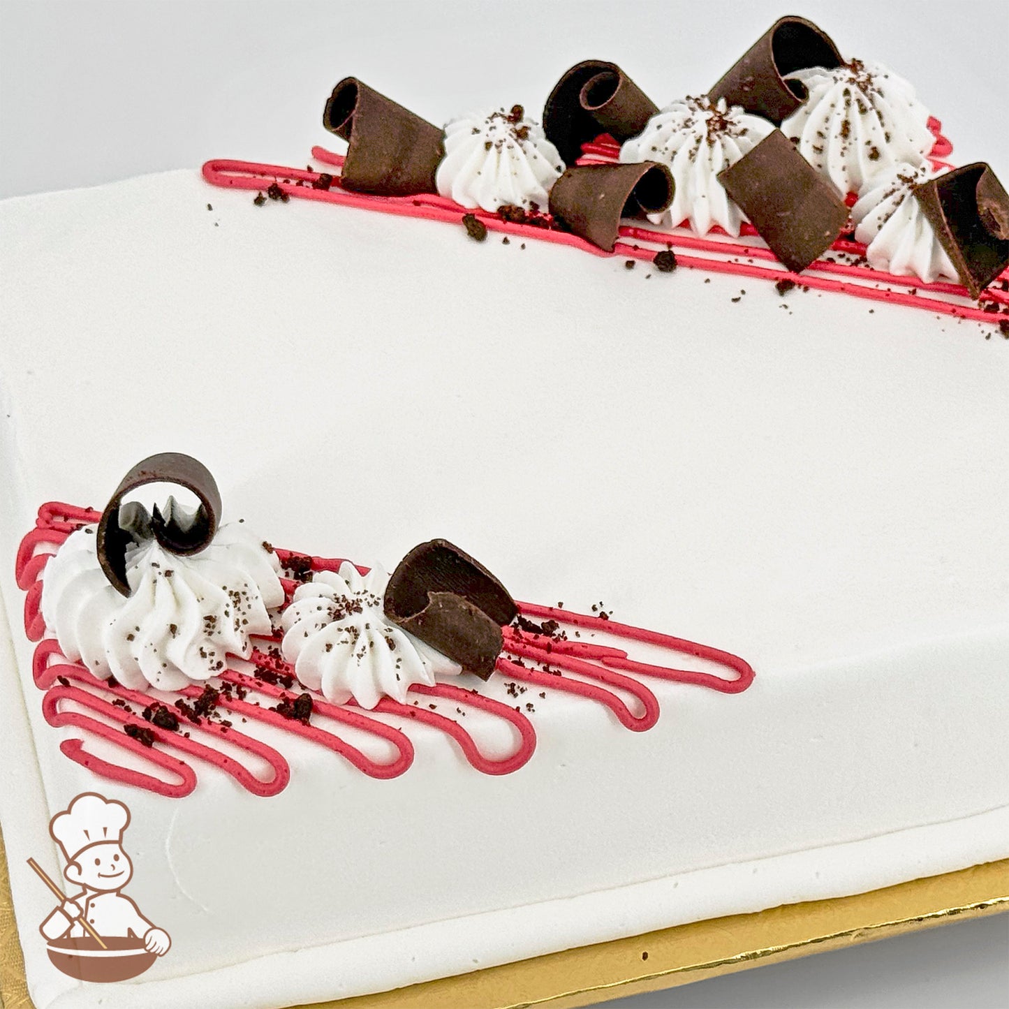 White sheet cake with pink buttercream lines, dollops of white frosting, chocolate curls, and chocolate crumbs.