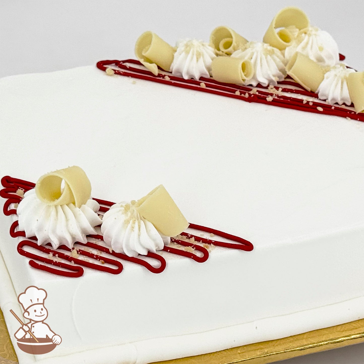 White sheet cake decorated with red buttercream lines, white chocolate curls, and dollops of piped white buttercream.