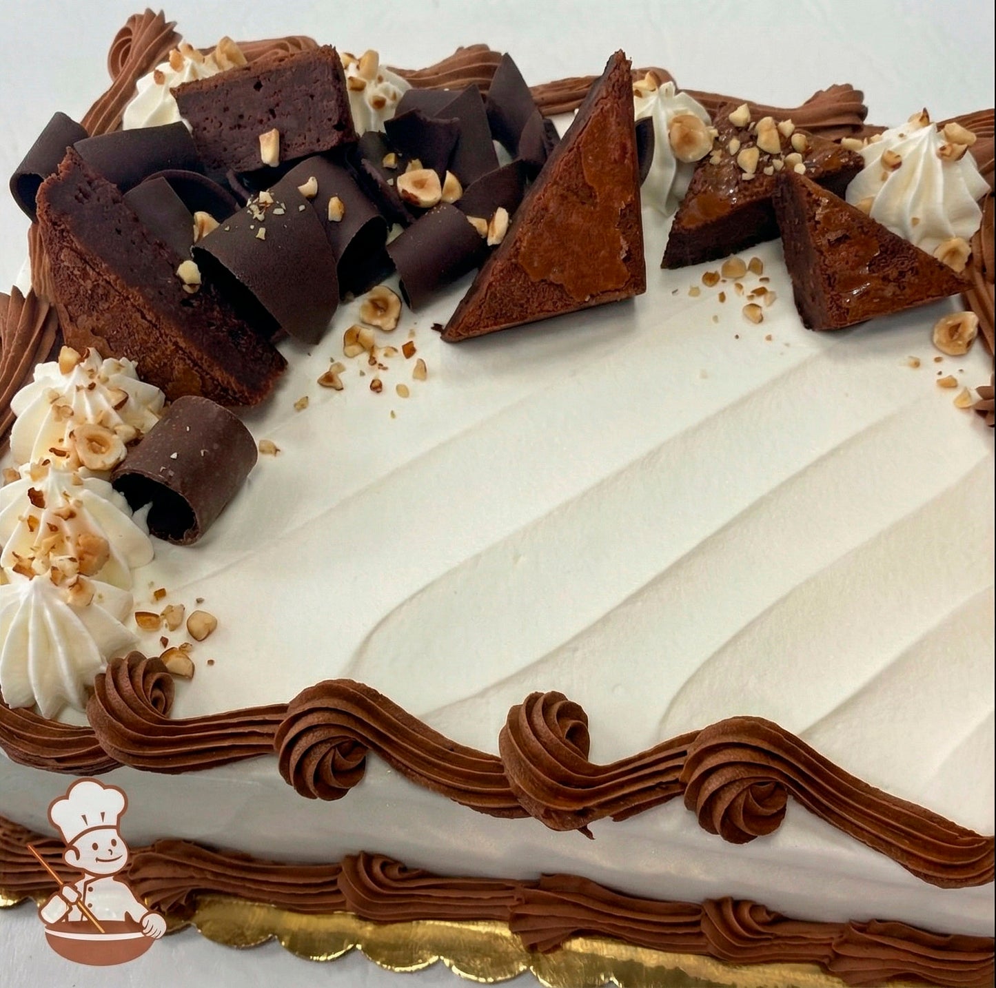 Sheet cake decorated with brownies, chocolate curls and diced hazelnuts.