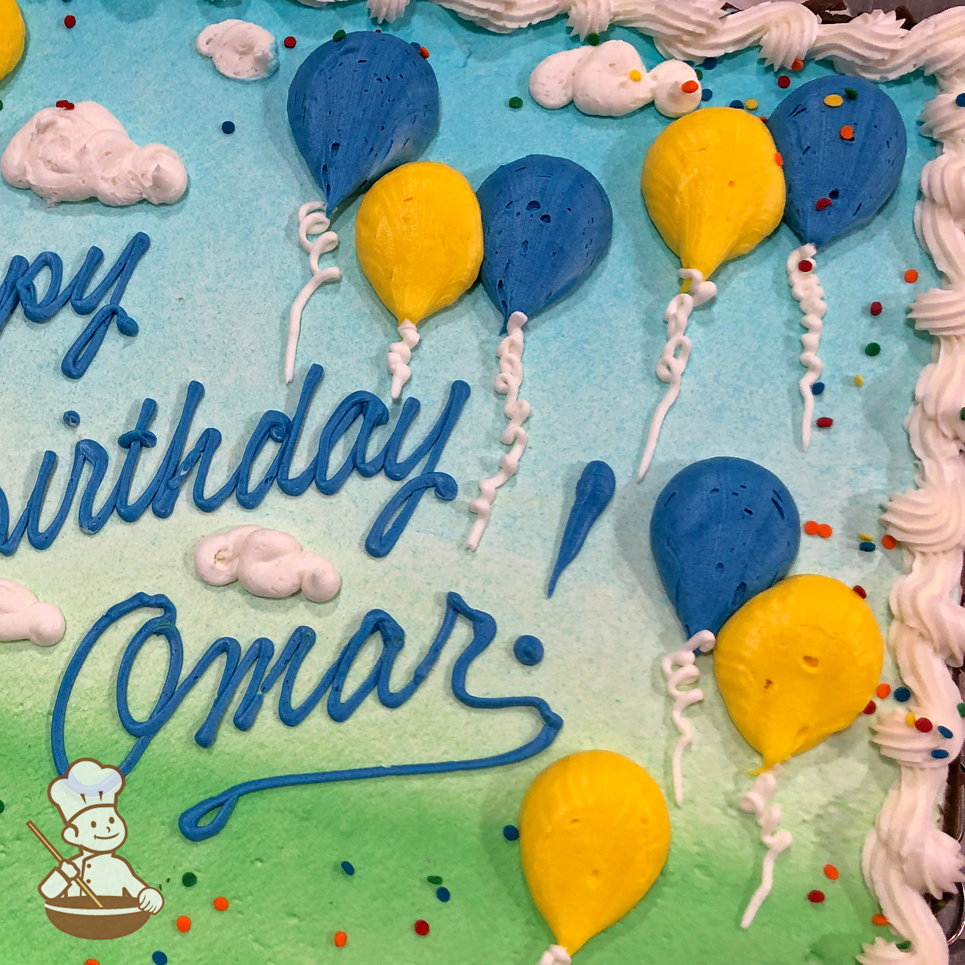 Birthday sheet cake with sprinkles and buttcream clouds and balloons against the grass and sky scene.