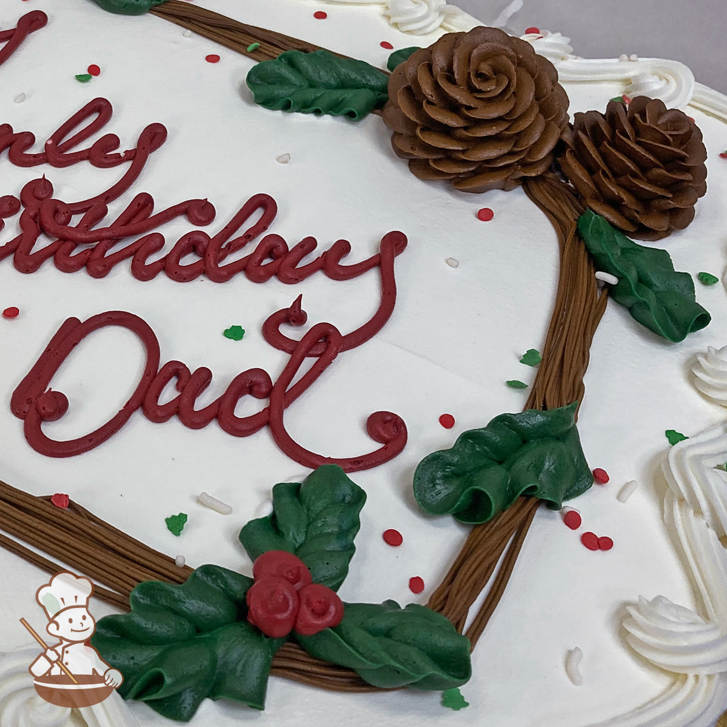 Birthday sheet cake with buttercream pinecone and holly in a frame with sprinkles.