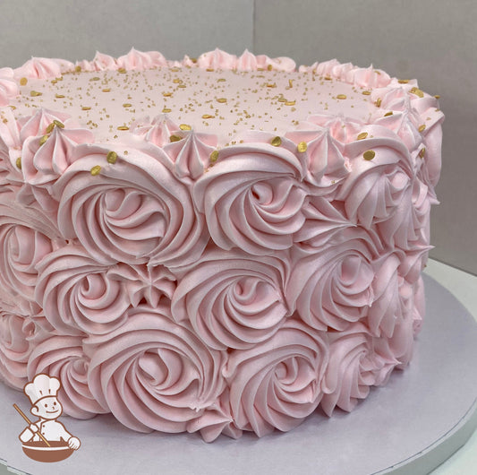 Single tier cake decorated with light-pink buttercream rosettes on the cake wall and the top is smooth, finished off with gold sprinkles.