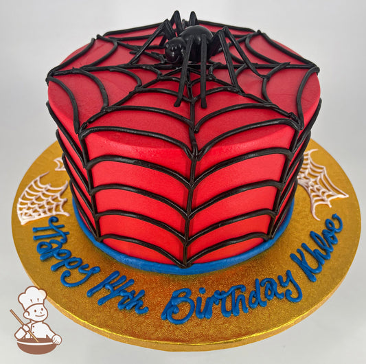 Single tier cake with smooth red icing, and decorated with hand-piped buttercream black webs and a toy plastic black spider on top.