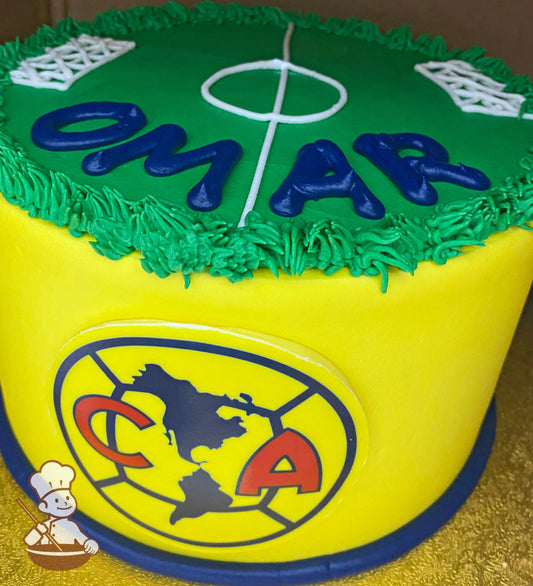 Cake with yellow icing, decorated with a printed image of the America team logo on the front of the cake and a soccer field on top of the cake.