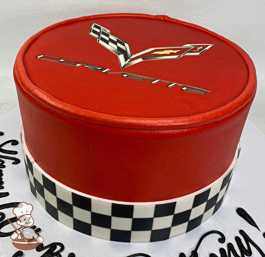 Cake with smooth red icing and decorated with the corvette logo on top and a printed checkered print around the bottom of the cake wall.
