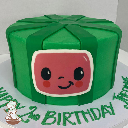 Single tier cake with smooth green icing and decorated with green fondant stripes and a printed image of the smiling Cocomelon logo face.