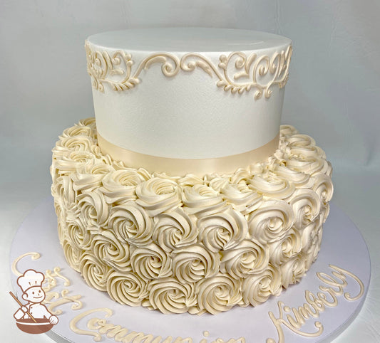 2-tier round cake with buttercream rosettes, has scrolls on cake wall at the top of the tier with an ivory ribbon on the base of the top tier.